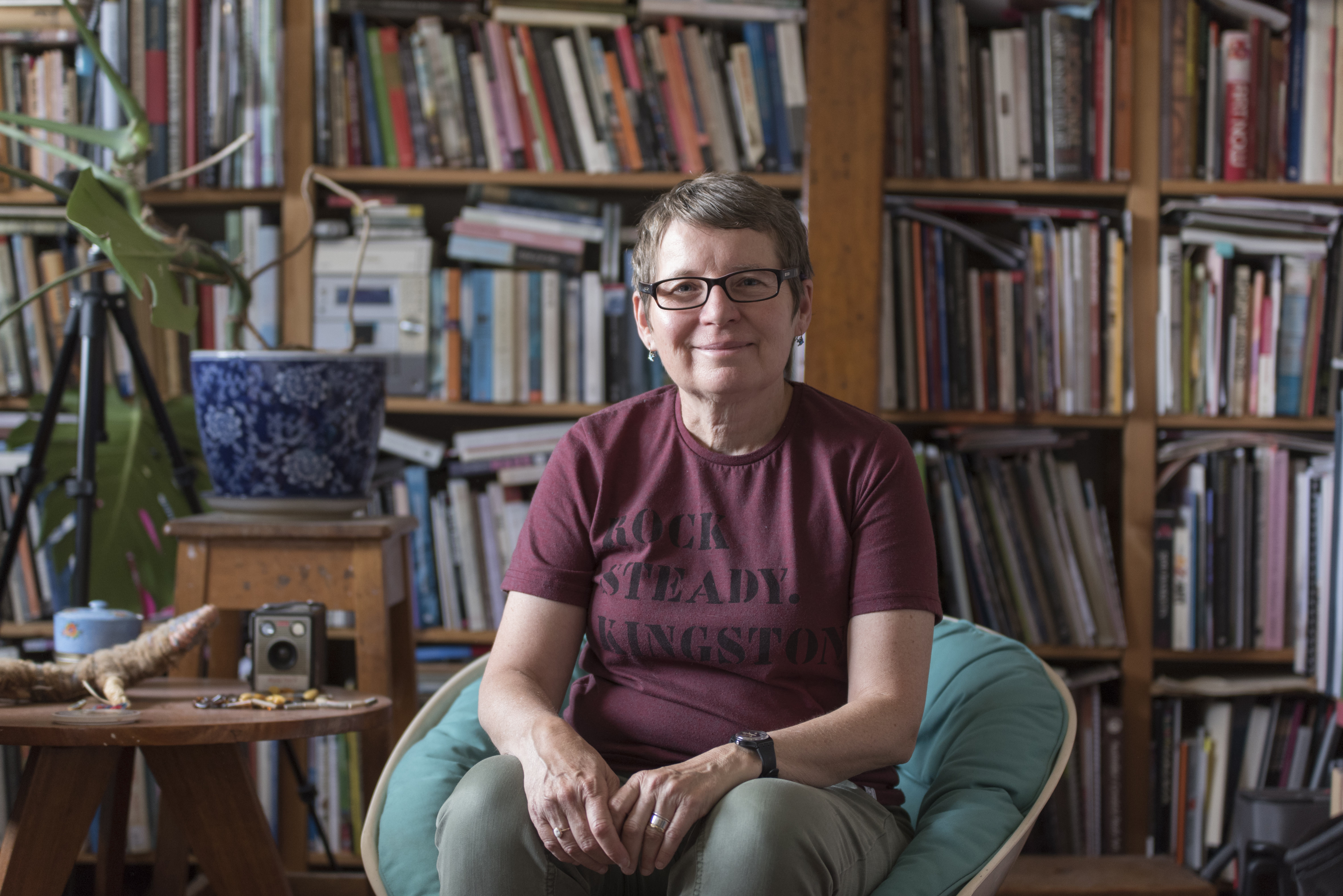 Woman (Julie Gough) sitting in front of book case